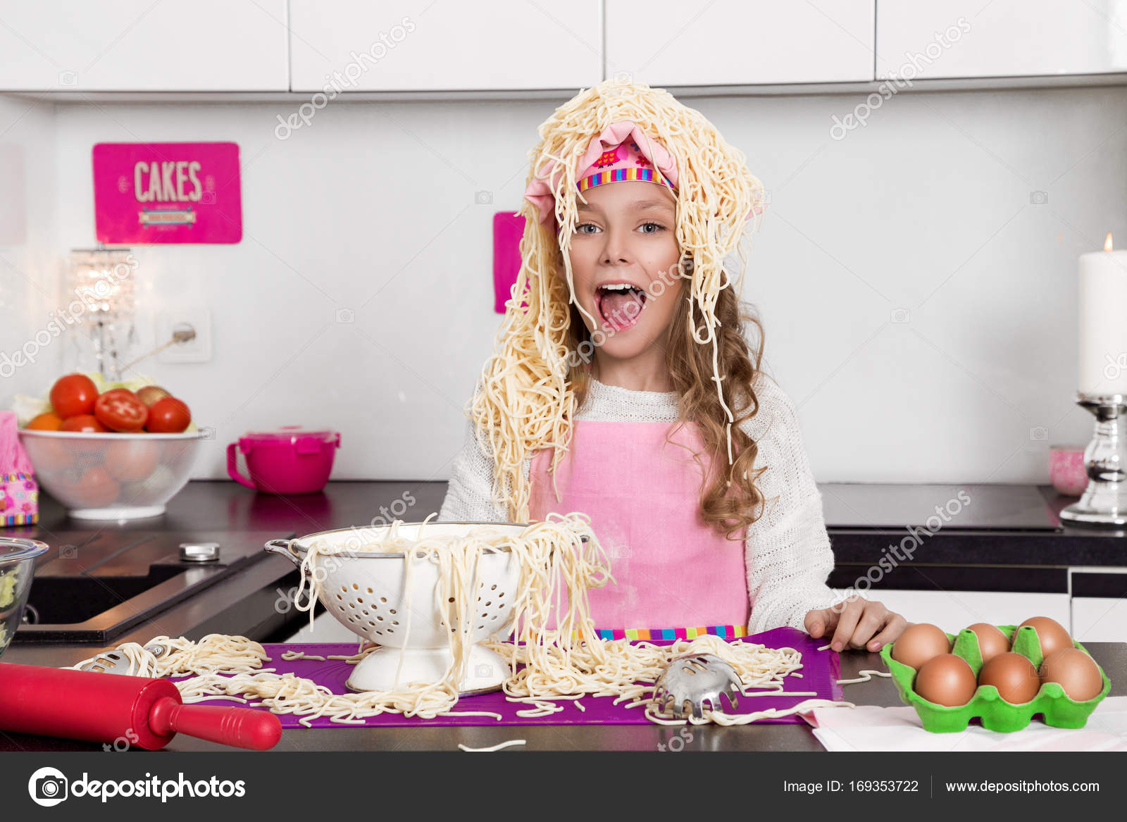 Beautiful funny girl daughter kid in aprons kitchen cooking in the kitchen  cookies and pasta noodles and cakes Stock Photo by ©marcink3333 169353722